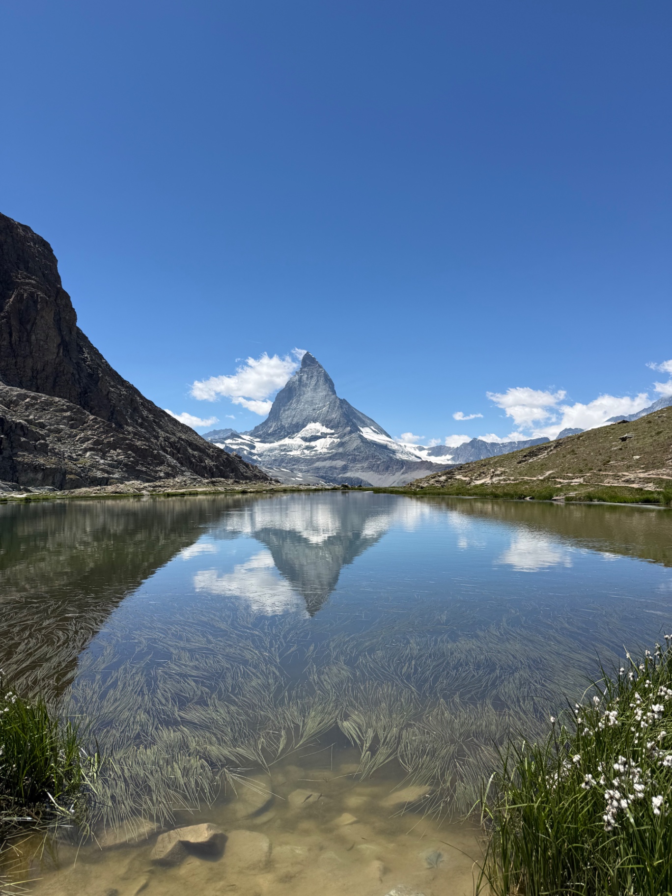 The Matterhorn reflected in a still alpine lake under a clear blue sky